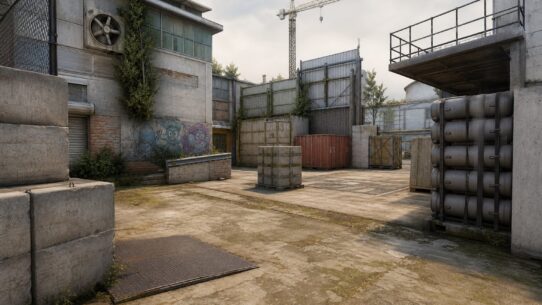 An industrial courtyard in a video game map with crates, barrels, graffiti, and a construction crane in the background