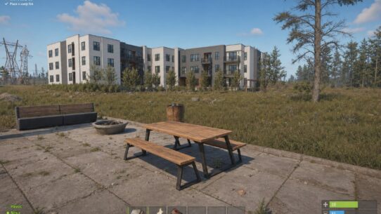 Rust gameplay screenshot showing a picnic table on a concrete patio near a multi-story building, with Getting Started tutorial objectives visible
